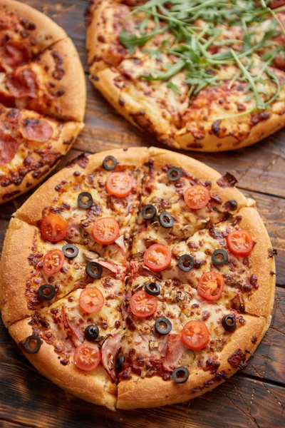 Sammansättning av tre olika sorters pizzor på träbord — Stockfoto