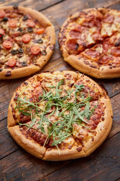 Sammansättning av tre olika sorters pizzor på träbord — Stockfoto