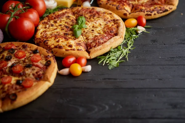 Segar disajikan, tiga berbagai pizza ditempatkan di antara bahan-bahan lezat. Tampilan atas — Stok Foto