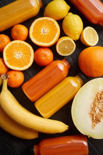 Mezcla de frutas y jugos de color naranja y amarillo sobre fondo de madera negro —  Fotos de Stock