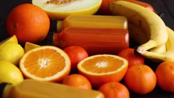 Mélange de fruits et jus de couleur orange et jaune sur fond de bois noir — Video