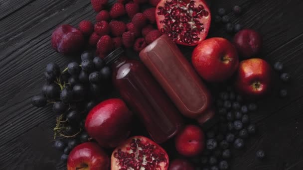 Διάφορα φρέσκα κόκκινα, μωβ μαύρα φρούτα. Μείγμα φρούτων και εμφιαλωμένων χυμών σε μαύρο — Αρχείο Βίντεο