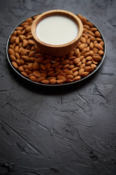 Composition des graines d'amandes et du lait, placées sur fond de pierre noire . — Photo