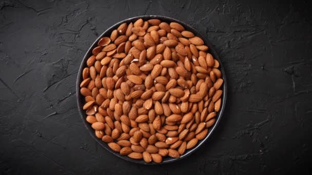 Whole almond nuts in black plate placed on black stone table — 비디오