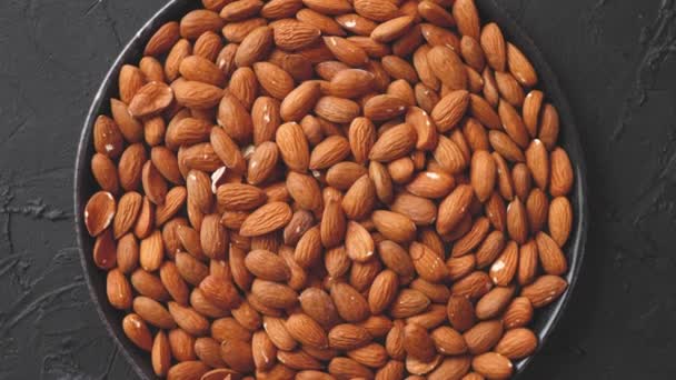 Whole almond nuts in black plate placed on black stone table — Stock Video