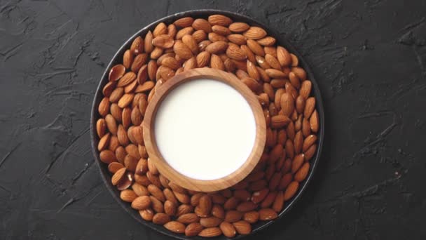 Composición de semillas de almendras y leche, colocada sobre fondo de piedra negra . — Vídeos de Stock