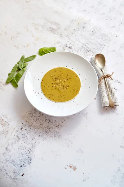 Cremige Suppe mit grüner Erbse in einem weißen Keramikteller — Stockfoto