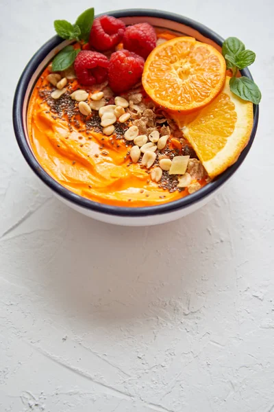Чаша со свежим здоровым смузи или йогуртом. С апельсиновыми ломтиками, мандарином, малиной, чиа и орехами — стоковое фото