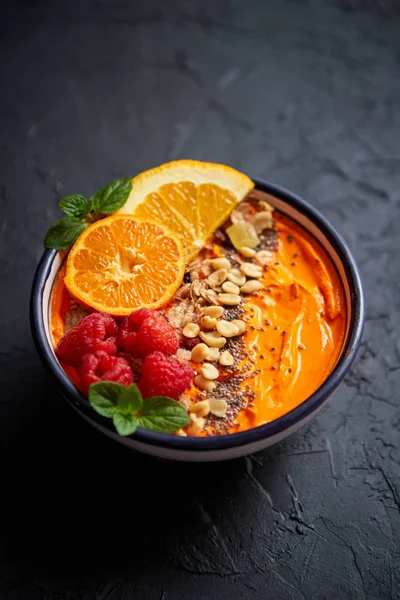 Kom met verse gezonde smoothie of yoghurt. met sinaasappelschijfjes, mandarijn, frambozen, chia en noten — Stockfoto