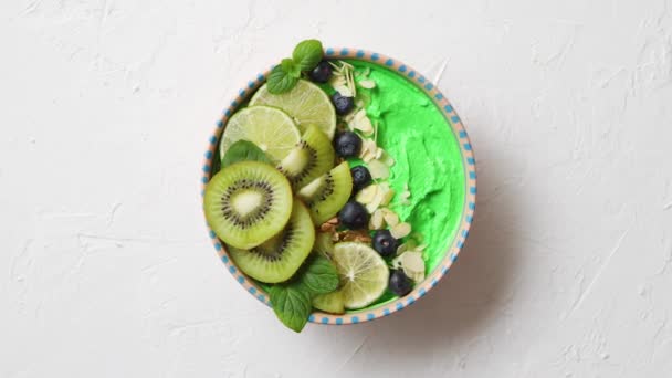 Zöld turmix vagy joghurtos tál. Friss kivivel, áfonyával, lime-mal és mandulapelyhekkel — Stock videók