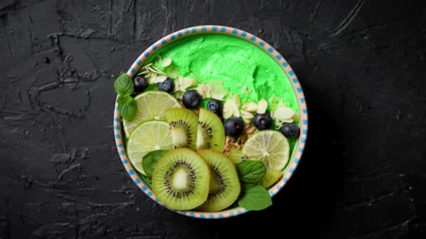 Зеленый смузи или миска йогурта. Со свежими киви, черникой, лаймом и миндальными хлопьями — стоковое видео