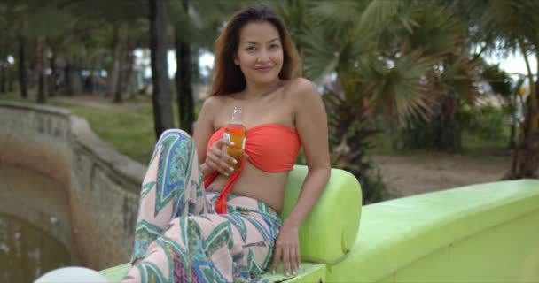 Счастливая этническая женщина пьет пиво на курорте — стоковое видео