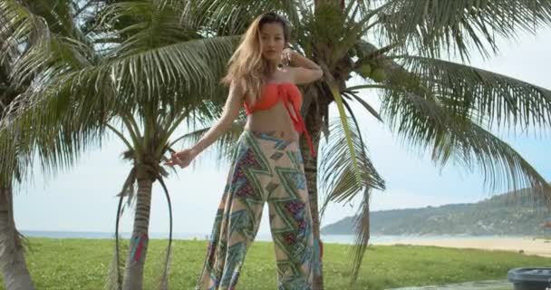 Тонкая этническая леди танцует рядом с пальмами — стоковое видео