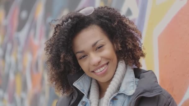 Beautiful smiling young womant with afro haircut posing outdoor with graffiti — Stock Video