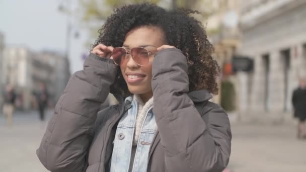 Hermosa chica con corte de pelo afro sentado en el banco en la calle de la ciudad — Vídeos de Stock