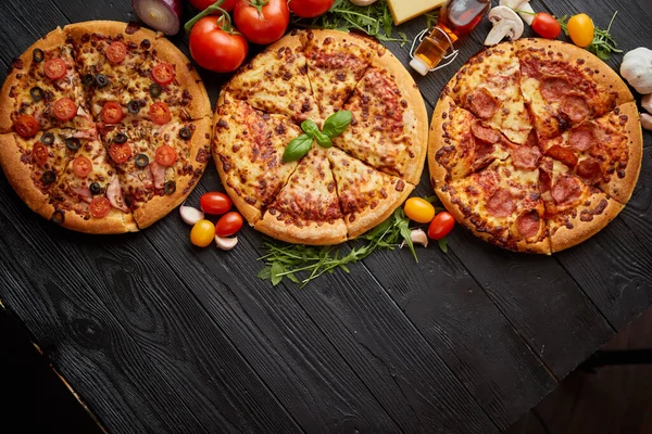 Segar disajikan, tiga berbagai pizza ditempatkan di antara bahan-bahan lezat. Tampilan atas — Stok Foto