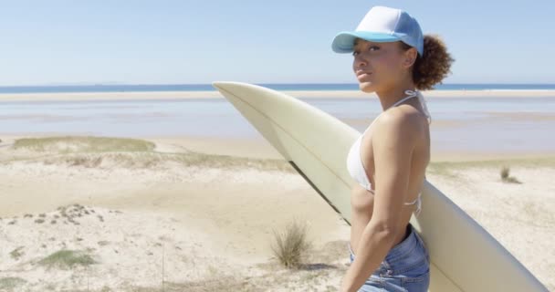 Улыбающаяся спортивная женщина обнимает доску для серфинга — стоковое видео