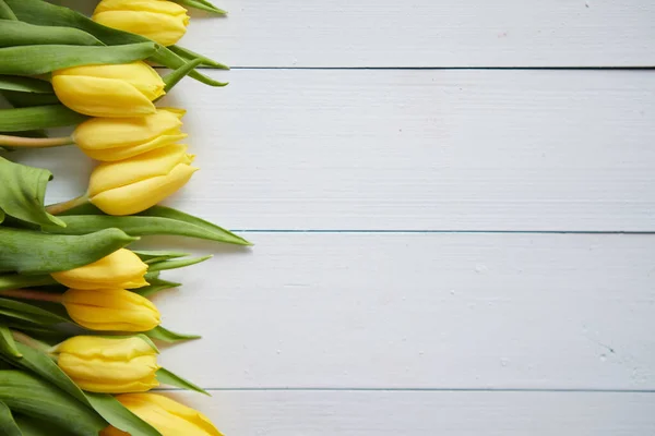 Рядок свіжих жовтих тюльпанів на білому дерев'яному столі — стокове фото