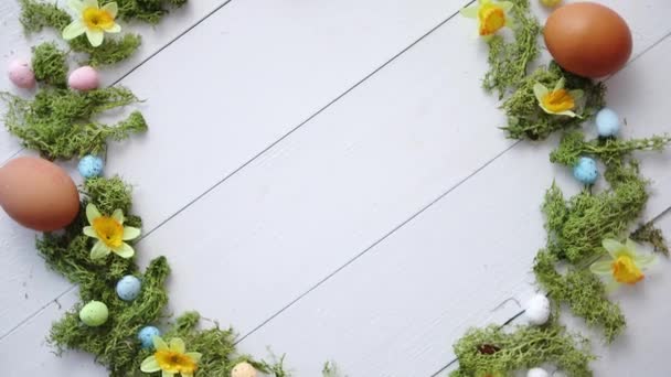 Couronne d'oeufs de Pâques décoratifs colorés sur fond de table en bois blanc — Video