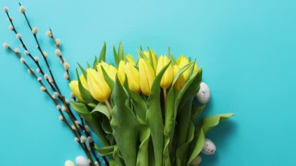 Decoración contept de vacaciones con huevos de Pascua y tulipanes amarillos sobre azul — Vídeo de stock