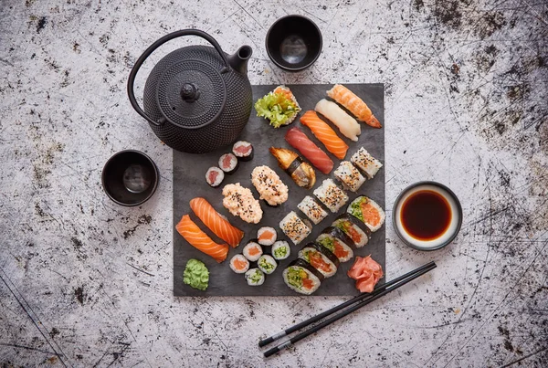 Surtido de diferentes tipos de rollos de sushi colocados en tablero de piedra negro — Foto de Stock