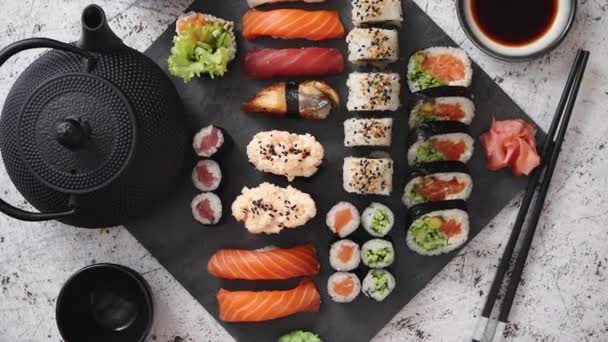Surtido de diferentes tipos de rollos de sushi colocados en tablero de piedra negro — Vídeos de Stock