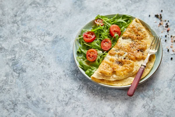 Omeleta de ovo clássico servido com tomate cereja e salada de rúcula no lado — Fotografia de Stock