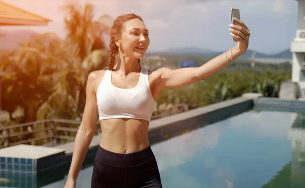 Vrolijke sportvrouw neemt selfie op het zwembad — Stockfoto
