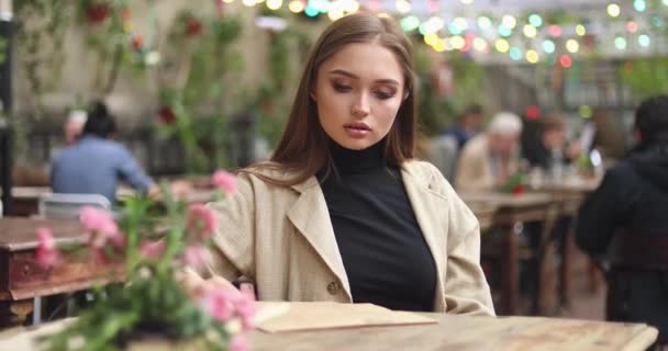 Lächelndes Mädchen untersucht Speisekarte im Kaffee — Stockvideo