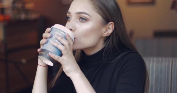 Joven y hermosa chica con ojos azules sentado en la cafetería con taza de café — Vídeo de stock