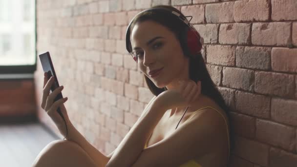 Kvinna lyssnar på musik nära väggen — Stockvideo