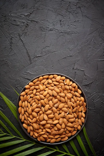 Composition des écrous aux amandes entières en plaque noire placée sur une table en pierre noire — Photo