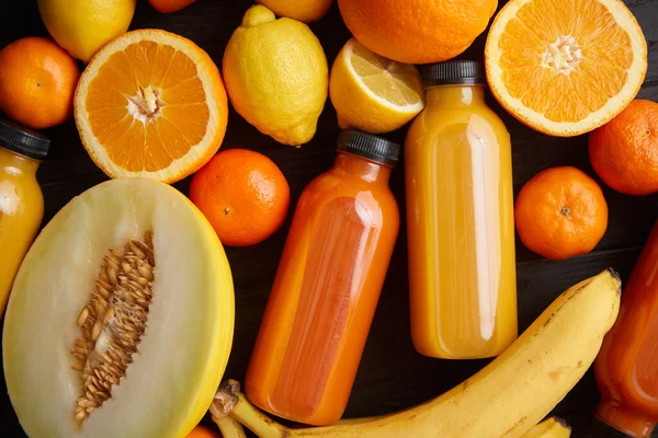Mezcla de frutas y jugos de color naranja y amarillo sobre fondo de madera negro —  Fotos de Stock