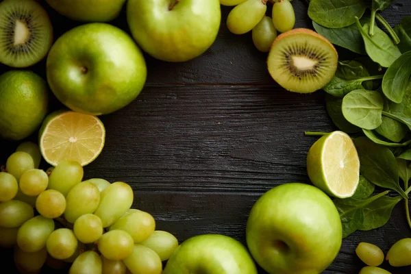 Fruits et légumes verts mélangés placés sur une table en bois noir — Photo