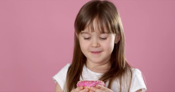 Roztomilý mladý kavkazský dívka chycený jíst sladký růžový kobliha — Stock video