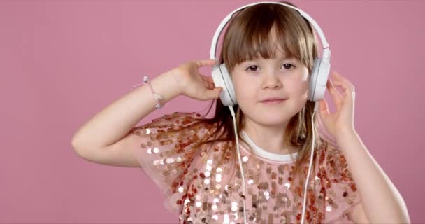 Cute little girl pozowanie i taniec ze słuchawkami podczas słuchania muzyki — Wideo stockowe