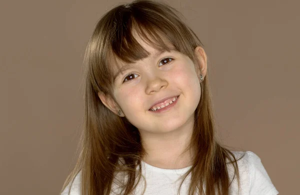 Retrato de um pouco bonito 7 anos de idade menina em uma tshirt branca, posando e sorrindo — Fotografia de Stock