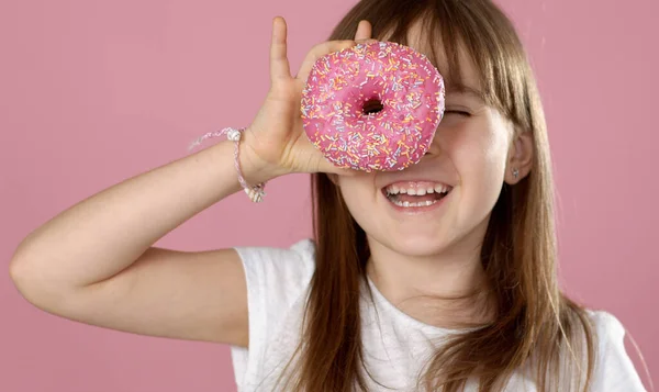 Jovem linda menina loira feliz e animado 6 ou 7 anos de idade segurando donut em seus olhos — Fotografia de Stock