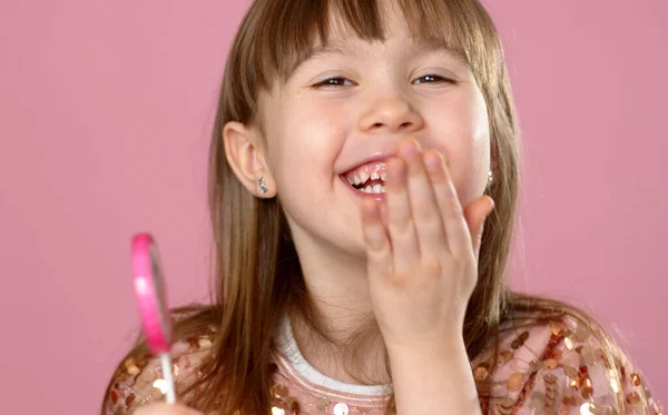 Pembe lolipop şekeriyle poz veren sevimli genç kız. Tüm mutlulukla kameraya gülümsüyor. — Stok fotoğraf