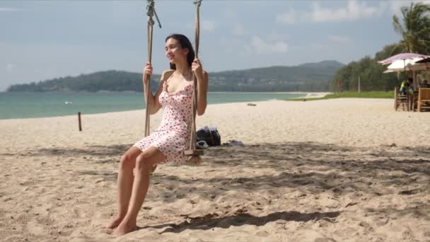 Side view bájos sötét hajú nő a sundress ül a swing és élvezi a napsütéses nap — Stock videók