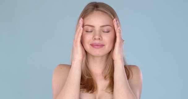 Adorable young woman portrait in studio. Doing massage of her temples with enjoyment — Stock Video