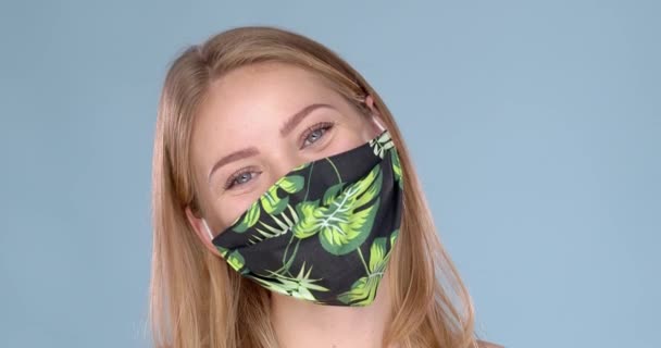 Studio porträtt av ung kvinna bär en ansikte blomma mönstrad mask, tittar på kameran, närbild — Stockvideo