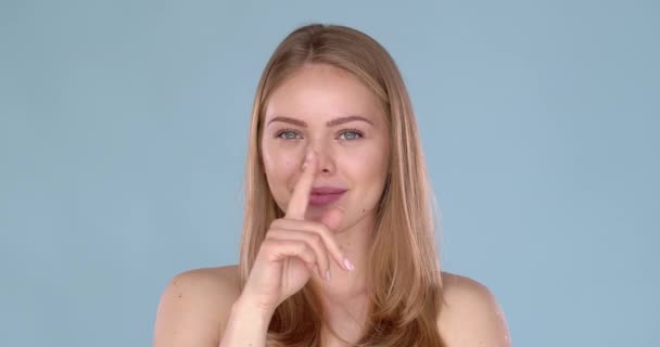 Hermosa mujer rubia haciendo un gesto tranquilo con el dedo en los labios — Vídeos de Stock