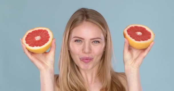 Lassú mozgás videó egy gyönyörű boldog mosolygós fiatal szőke nő grapefruit féllel — Stock videók