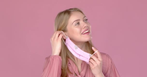 Schattig lachend jong meisje met haar gezichtsmasker tegen virussen. Video in slow motion — Stockvideo