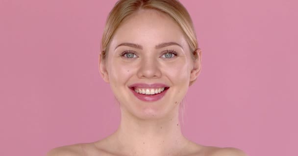 Slow motion video shot of smiling beautiful girl, isolated on pink background. Bare shoulders — Stock Video