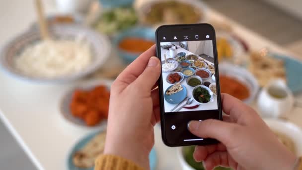 Mãos femininas tirar fotos de mesa cheia de pratos indianos por smartphone moderno — Vídeo de Stock