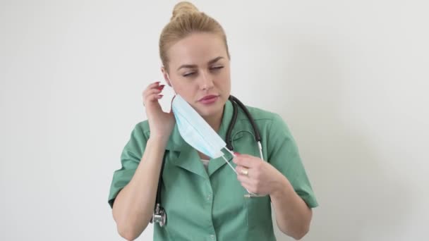 Retrato de jovem adulto médico feminino em verde médicos casaco coloca uma máscara médica — Vídeo de Stock