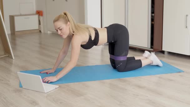 Atrakcyjna, wysportowana kobieta ćwiczy w domu podczas oczekiwania na lekcje fitness online — Wideo stockowe