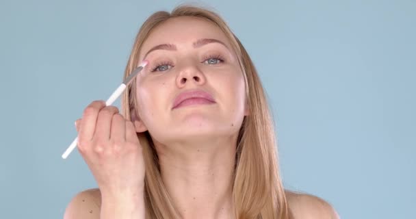 Avslappnad och glad kaukasiska kvinna tillämpa makeup på hennes ögon med hjälp av borste — Stockvideo